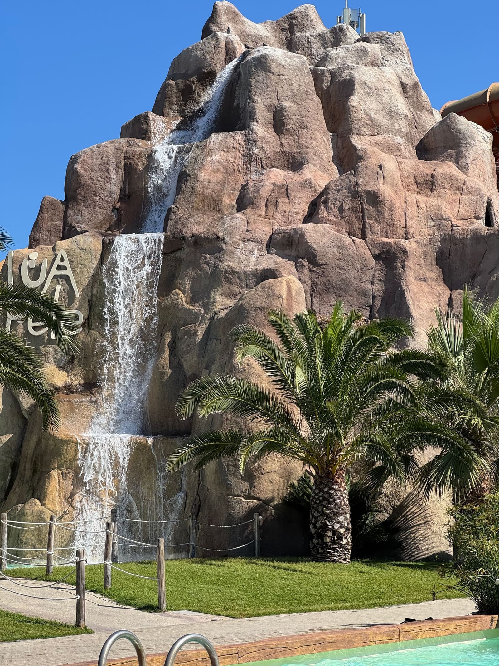 la cascata che scende dalla roccia del vulcano, in mezzo alle palme
