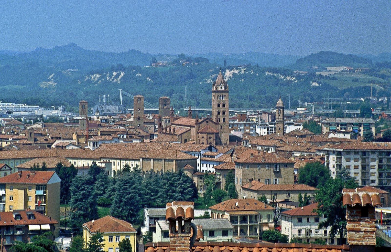 Alba dall'alto, con il campanile della cattedrale e le torri sopra i tetti, e dietro le colline delle Langhe