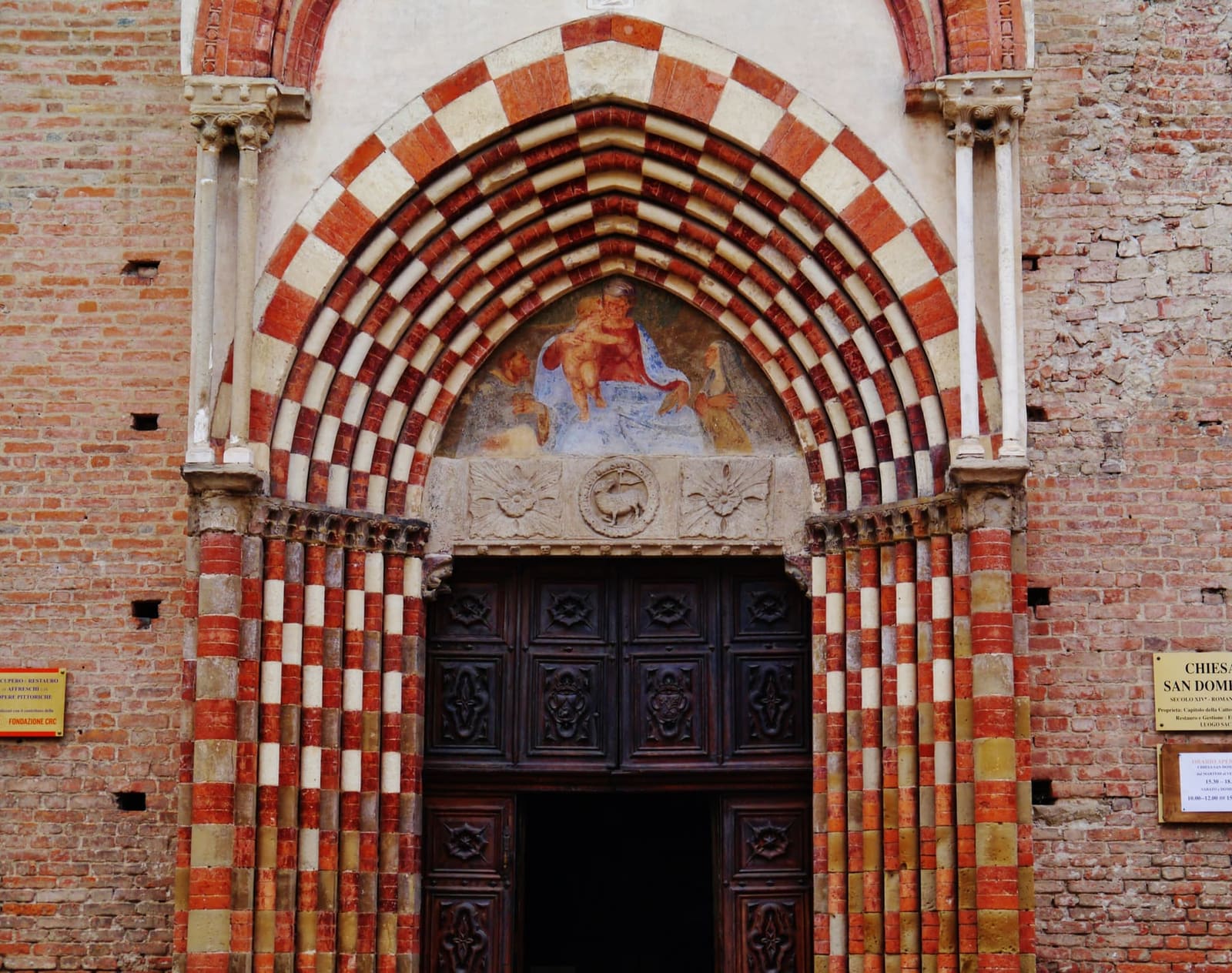 il portale di San Domenico, con gli archi a scacchi bianchi e rossi e l'affresco nella lunetta
