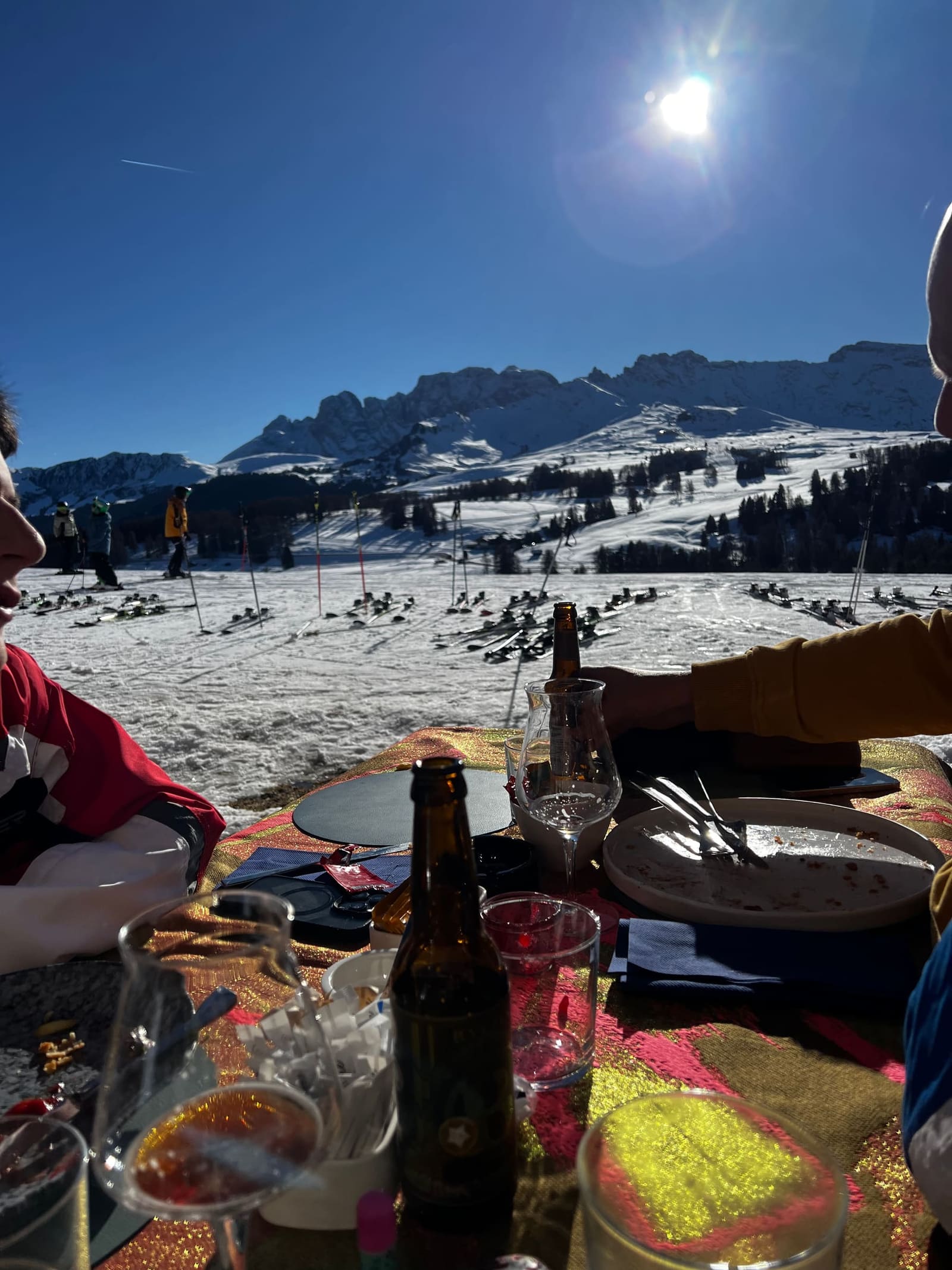 la tavola alla fine del pranzo, e la distesa di sci appoggiati sulla neve davanti
