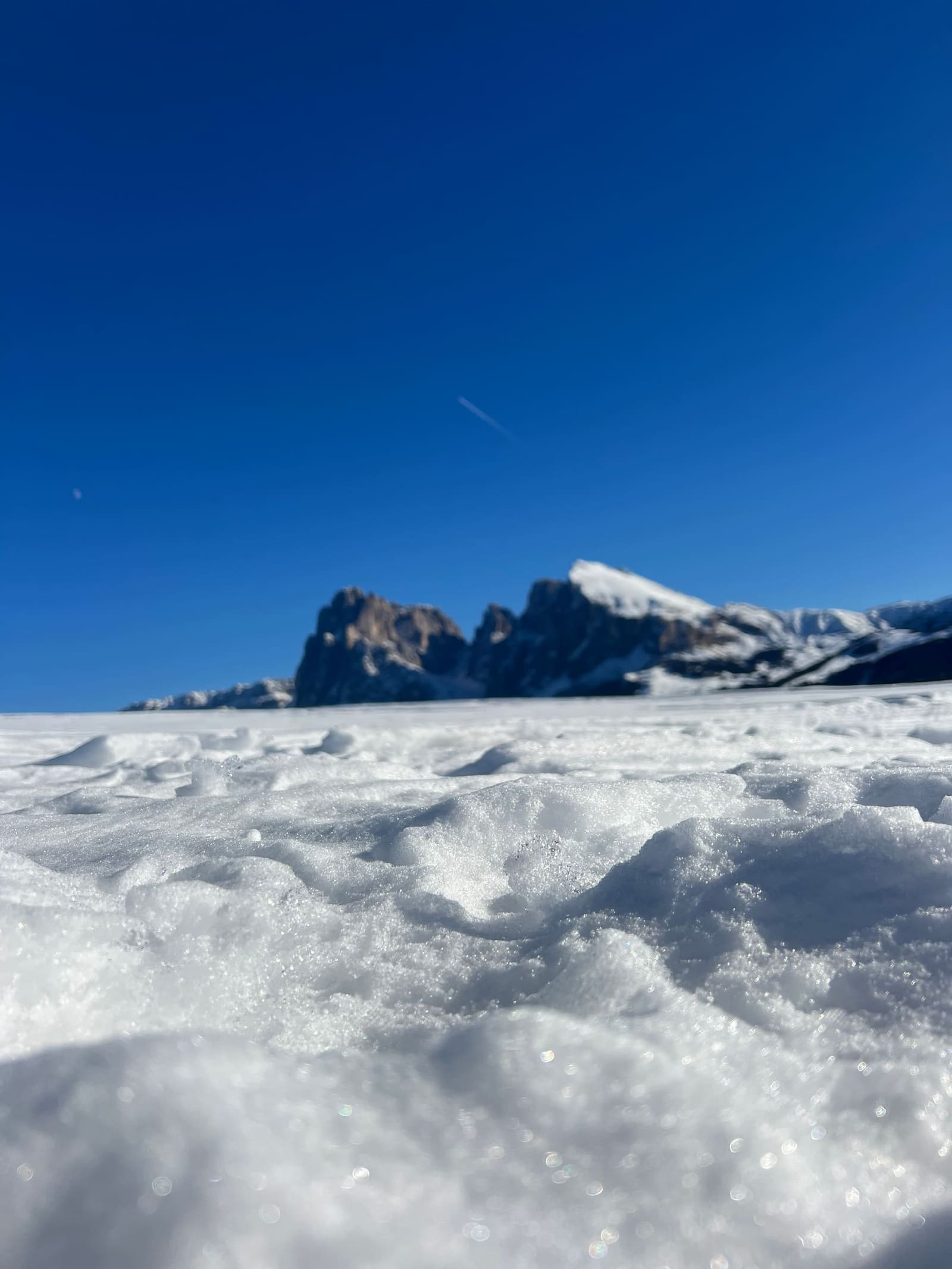 la neve granulosa in primo piano e il Sassolungo sfocato all'orizzonte