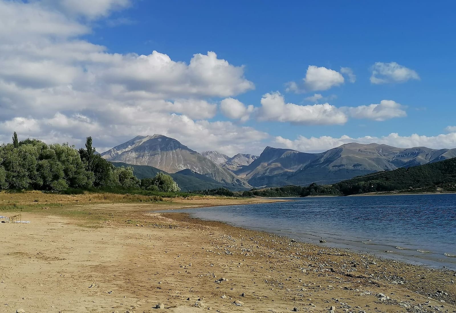 la riva di ghiaia e sabbia del lago di Campotosto, con le montagne sullo sfondo