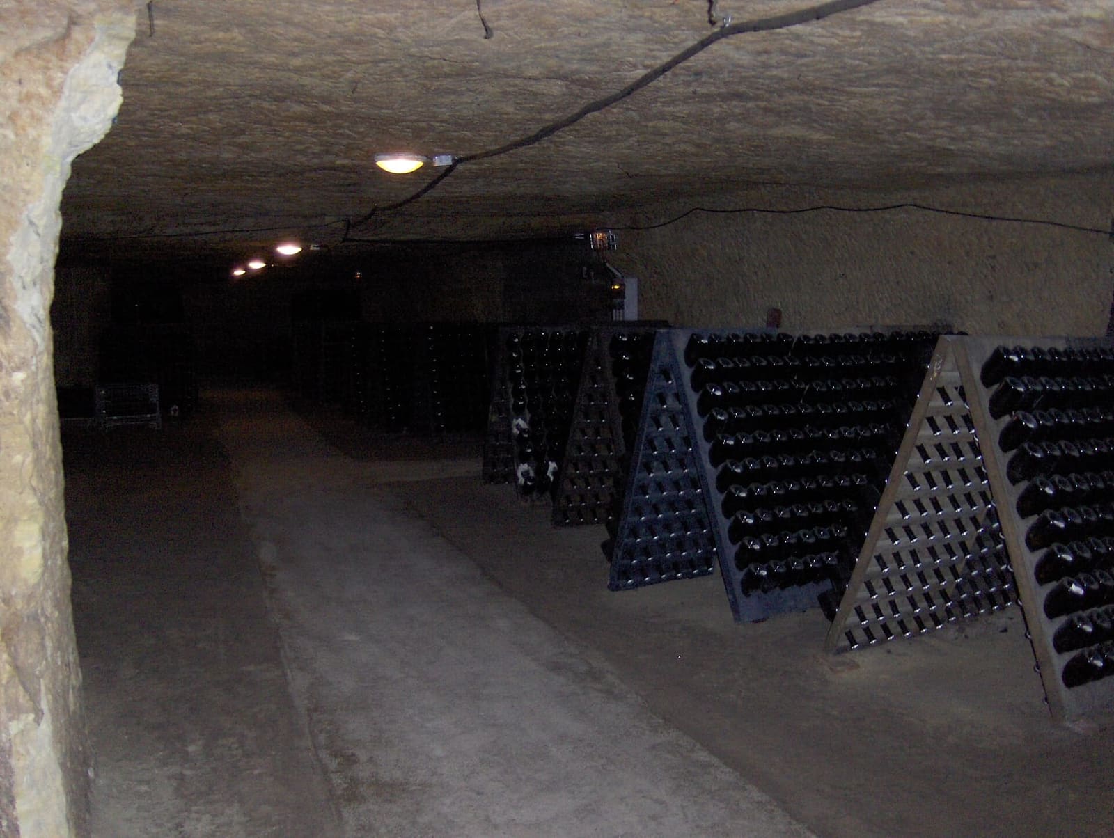des bouteilles sur pupitres dans une cave creusée dans le calcaire, dans le Vouvray
