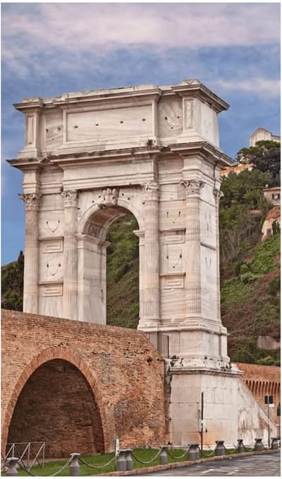 l'Arco di Traiano in marmo bianco sopra la banchina di mattoni, con il colle alle spalle