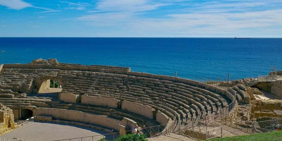 le gradinate scavate dell'anfiteatro con l'arena in basso e il Mediterraneo alle spalle