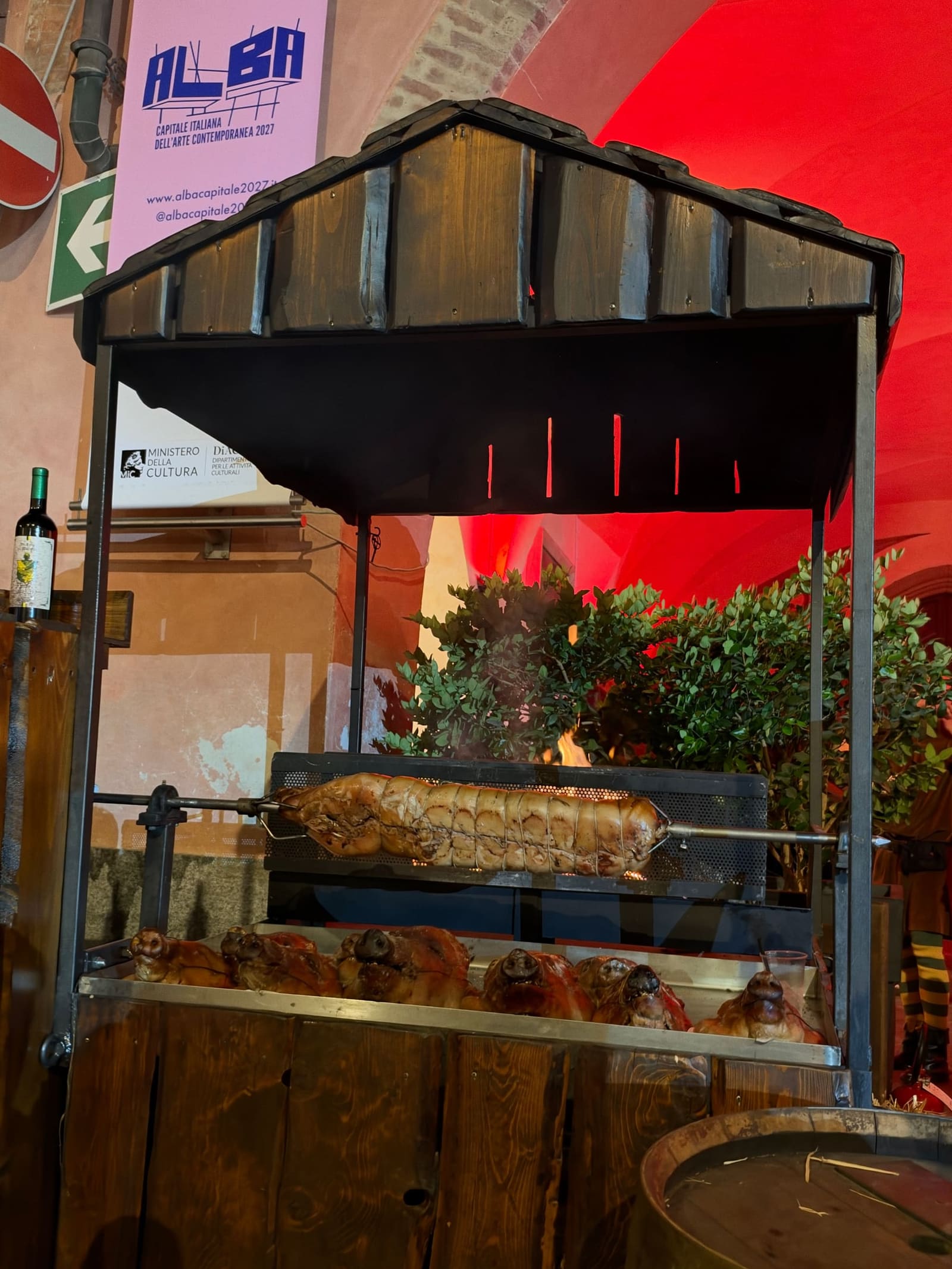 il girarrosto di uno stand sotto il portico del municipio, acceso di rosso
