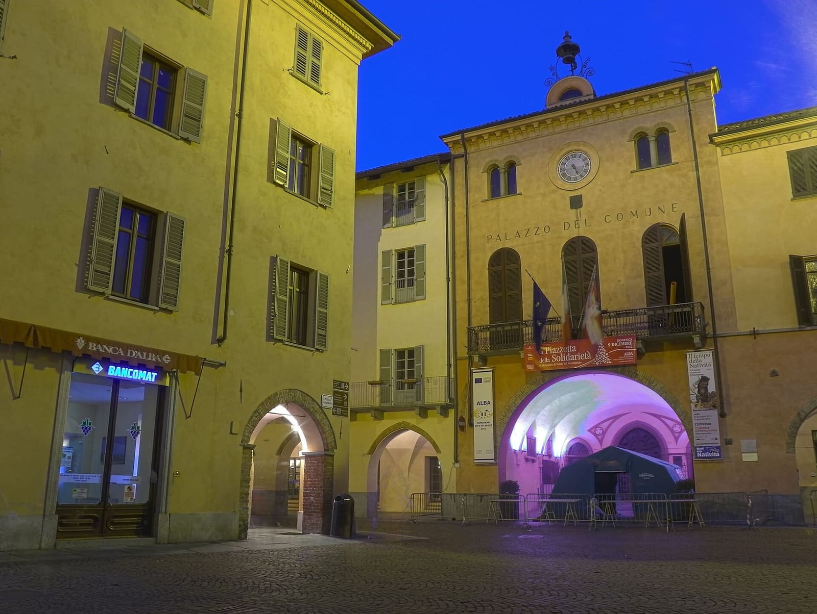 il Palazzo Comunale illuminato la sera, con l'arco del portico aperto sulla piazza