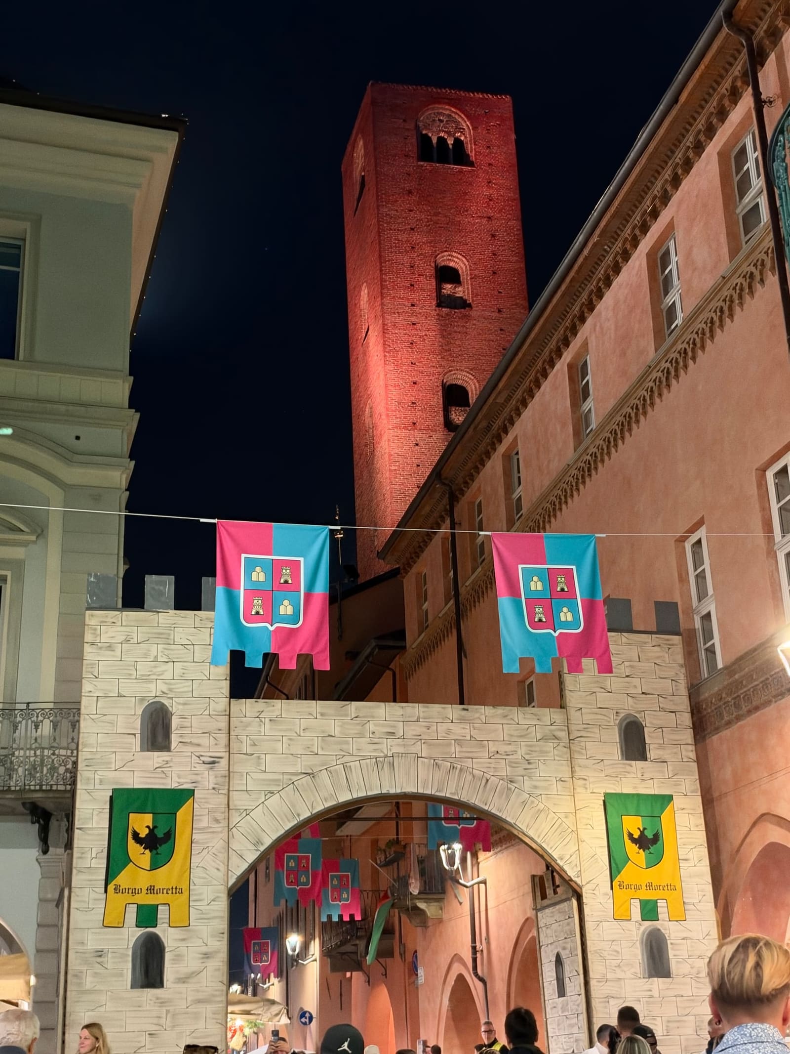 in via Cavour, a mock castle gate with the banners of the Borgo Moretta, beneath a tower lit up in red