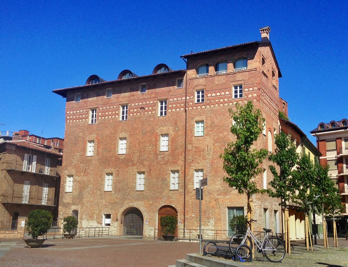 Piazza Pertinace, con il palazzo di mattoni e i suoi alberi