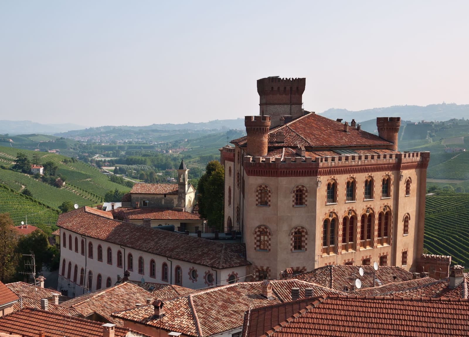 il castello Falletti dall'alto, sopra i tetti, con le vigne e le colline dietro