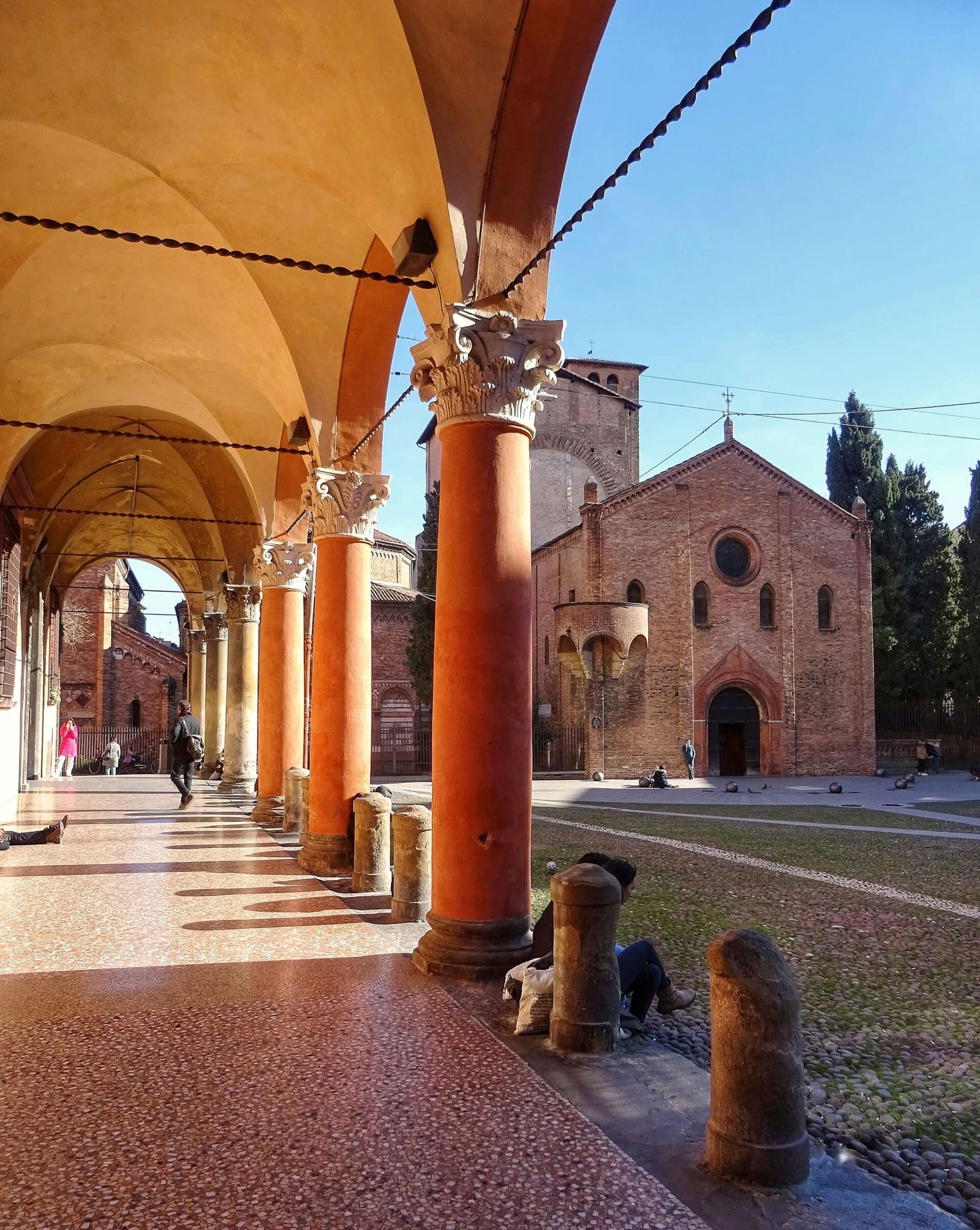 der Laubengang an der piazza Santo Stefano, mit der Basilika im Hintergrund, an einem Nachmittag im Februar