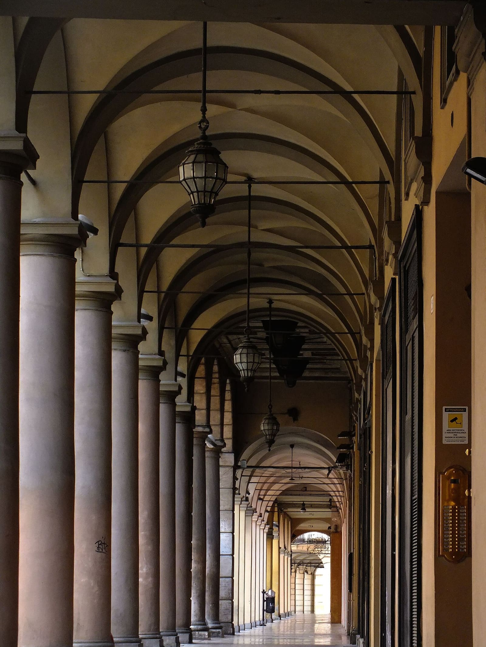 ein Laubengang im Zentrum von Bologna, mit den Kreuzgewölben und den hängenden Laternen