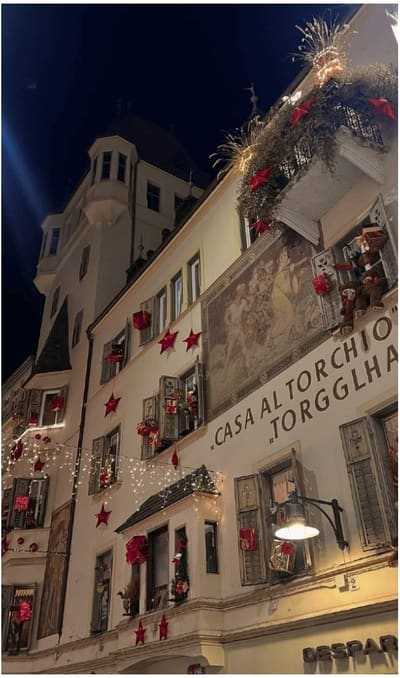 la facciata affrescata della Casa al Torchio addobbata con stelle rosse e luci