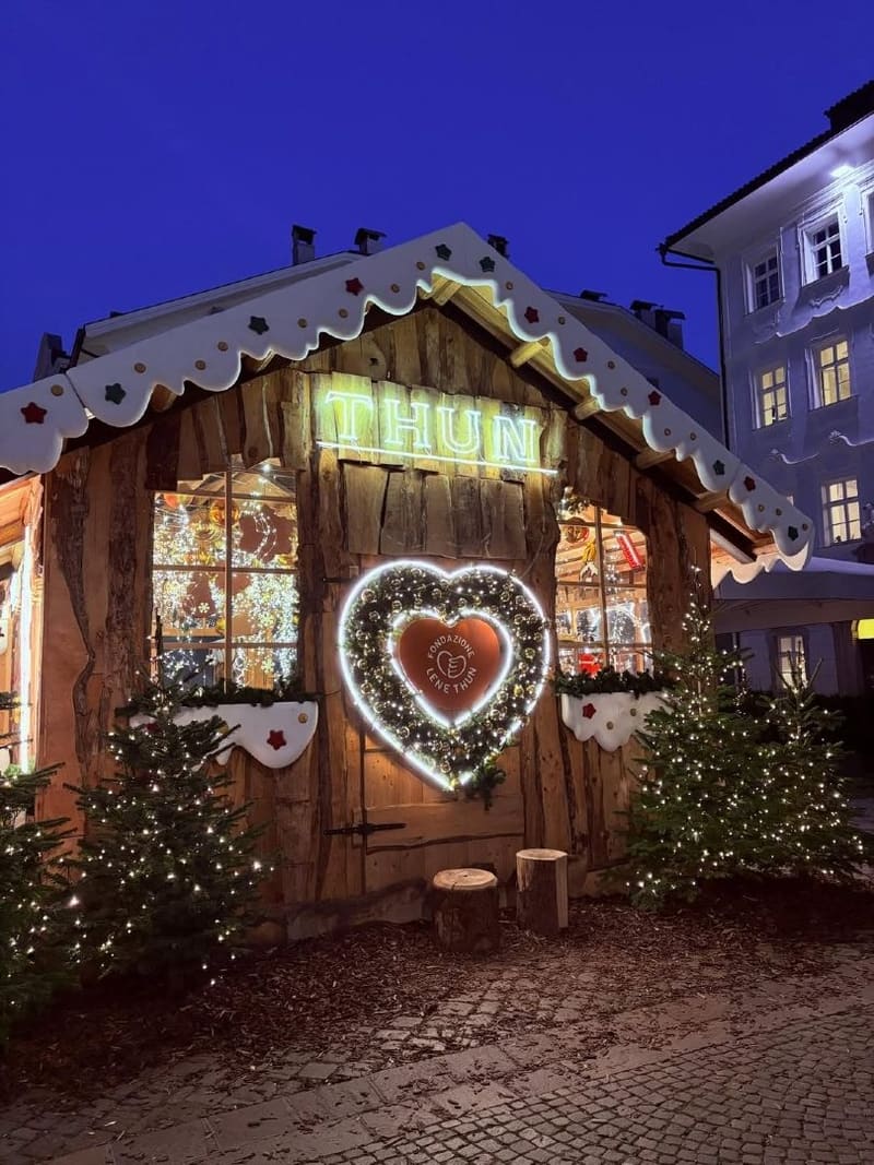 una casetta di legno del mercatino con un grande cuore luminoso sulla facciata