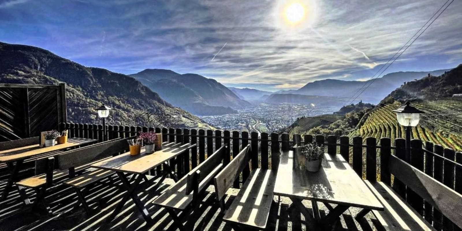 i tavoli di legno di una terrazza sopra i vigneti terrazzati, con la valle e la città sul fondo