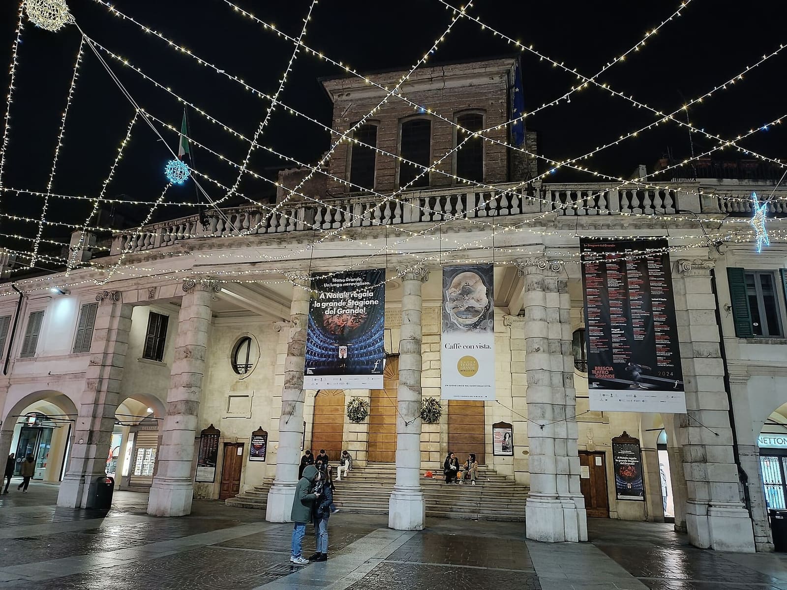 il portico del Teatro Grande in corso Zanardelli sotto la rete di luci di Natale, con le ghirlande sulle porte