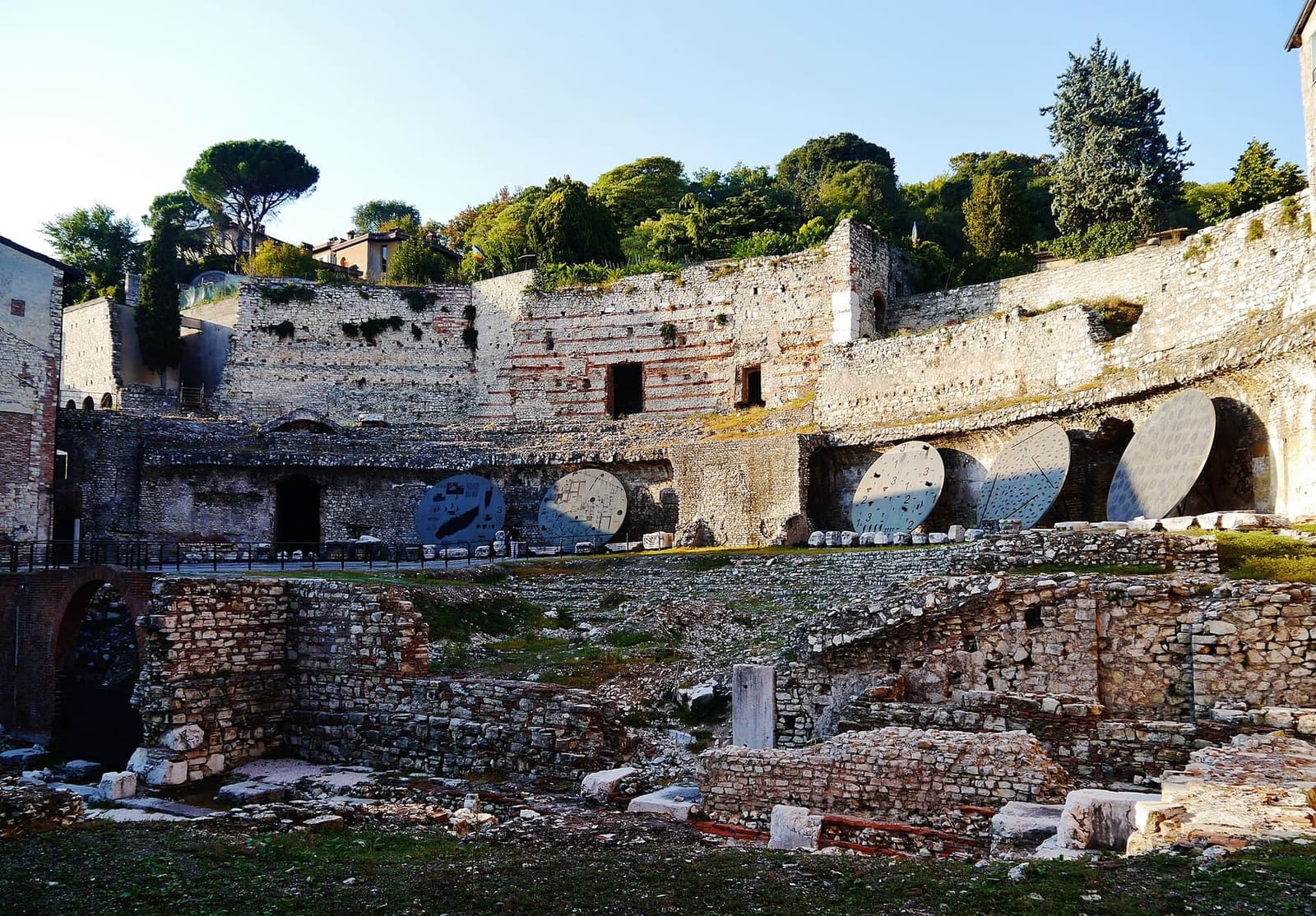 il teatro romano accanto al Capitolium, con le gradinate e le arcate ai piedi del colle Cidneo
