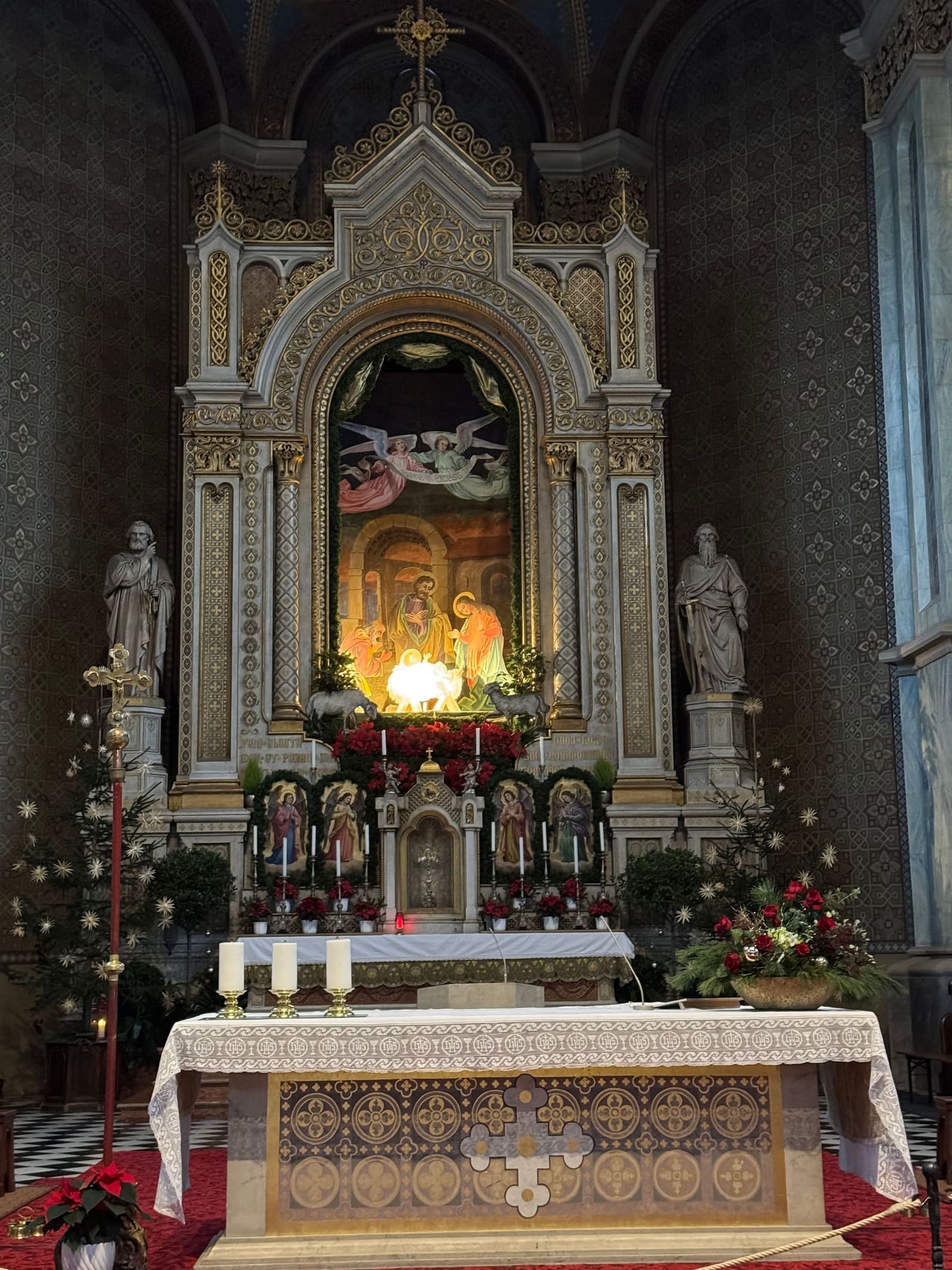 il presepe illuminato dentro la pala dell'altare maggiore, fra le stelle di Natale e le candele
