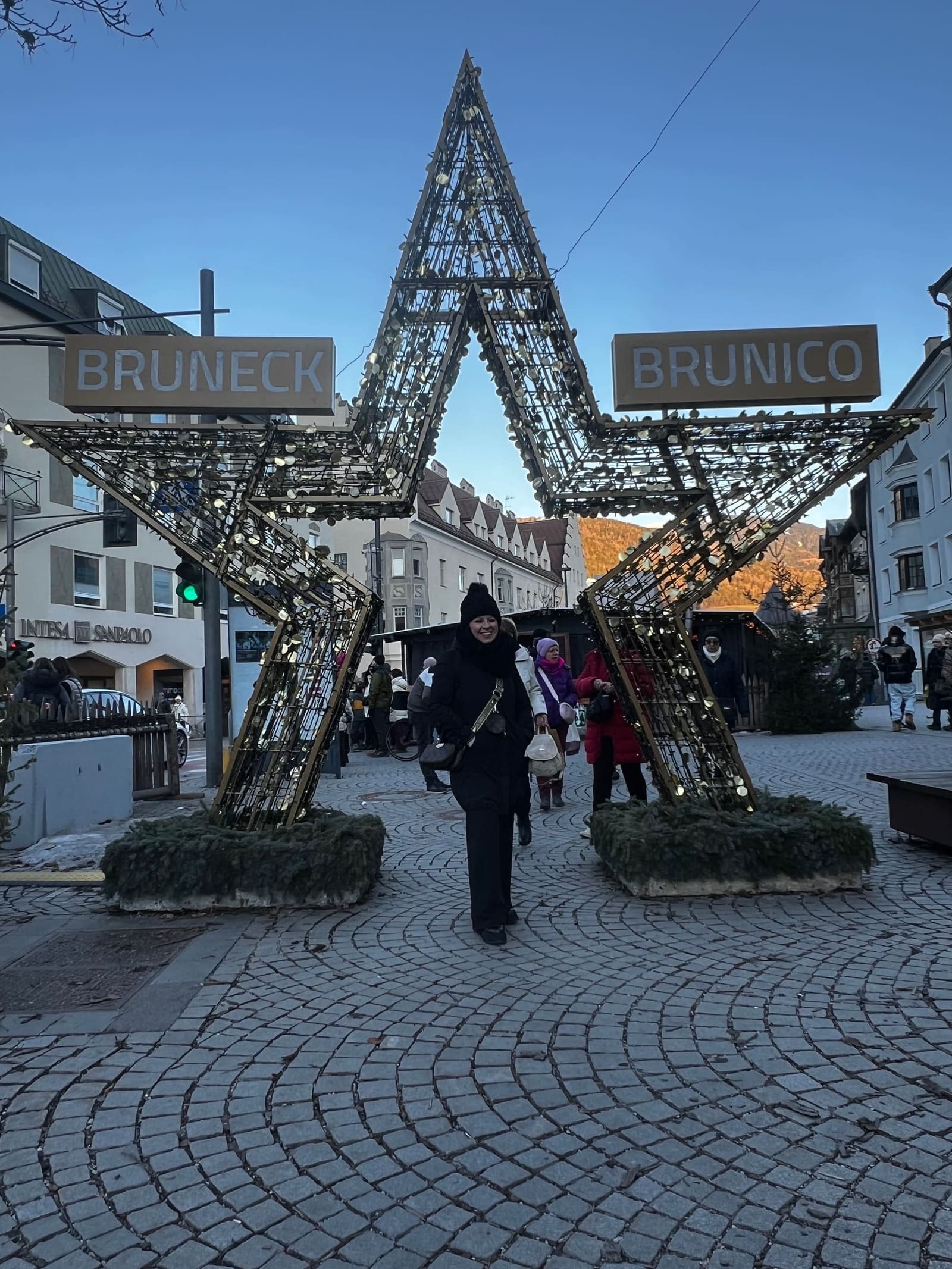 Marcella davanti alla grande stella luminosa, sotto le insegne Bruneck e Brunico