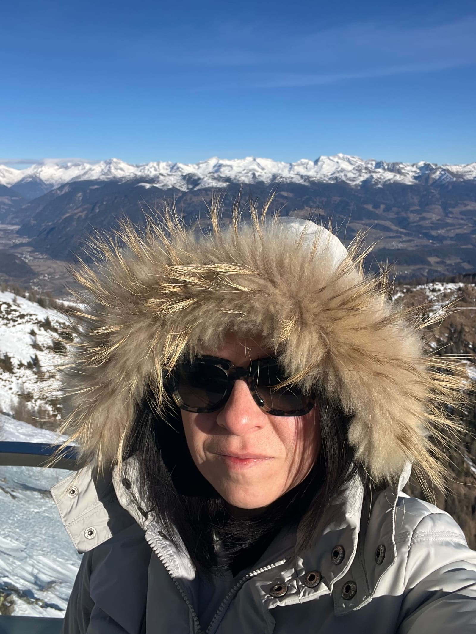 Marcella con il cappuccio di pelliccia, e la Val Pusteria sotto