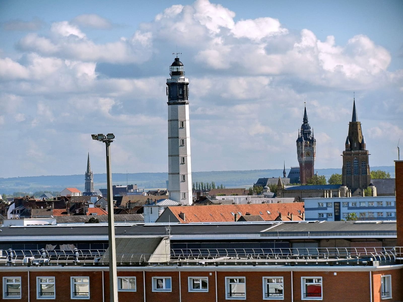 il faro sopra i tetti, con il beffroi e la torre di Notre-Dame a destra