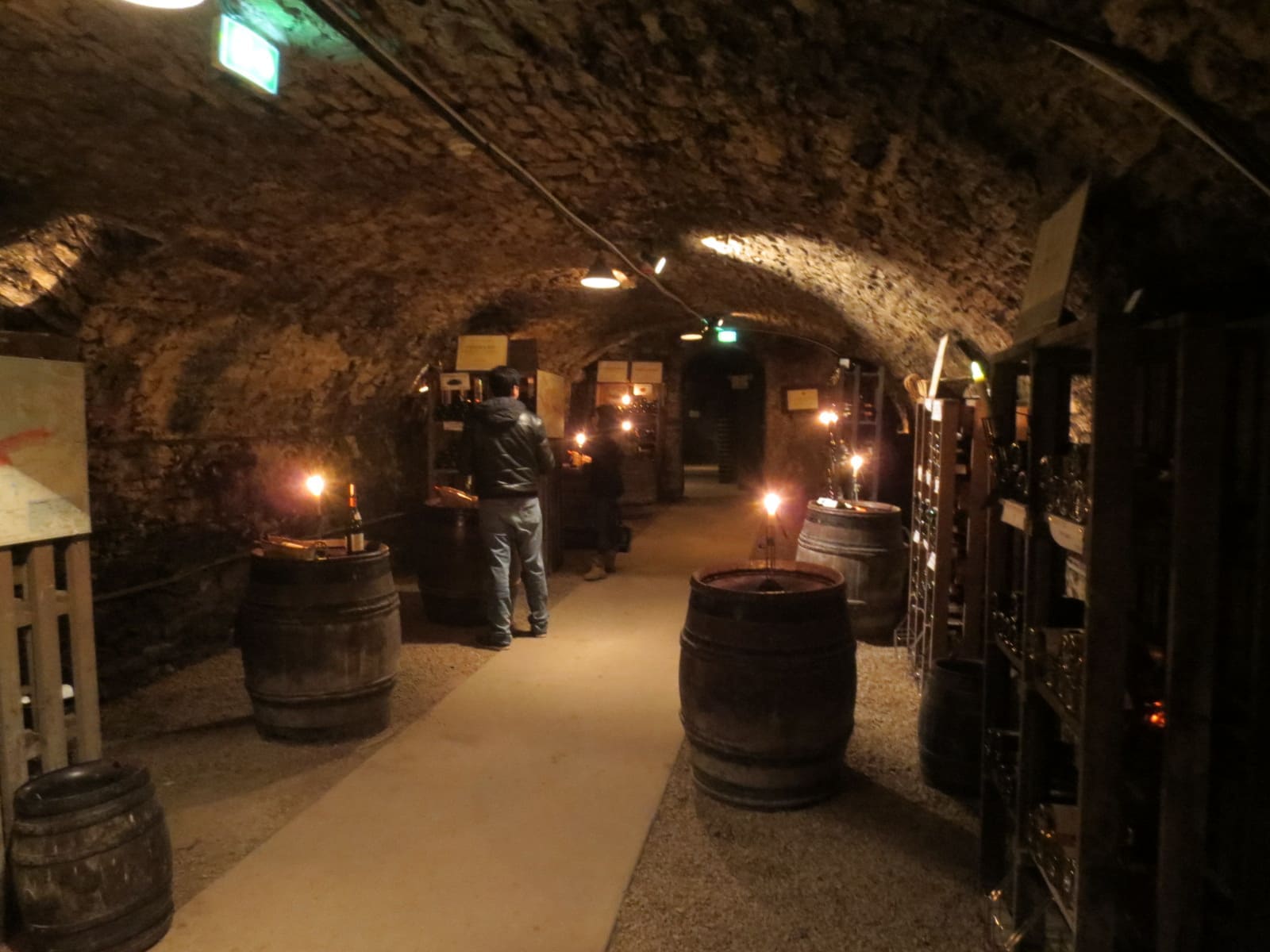 una galleria a volta delle cantine, con le botti e le candele accese lungo il passaggio