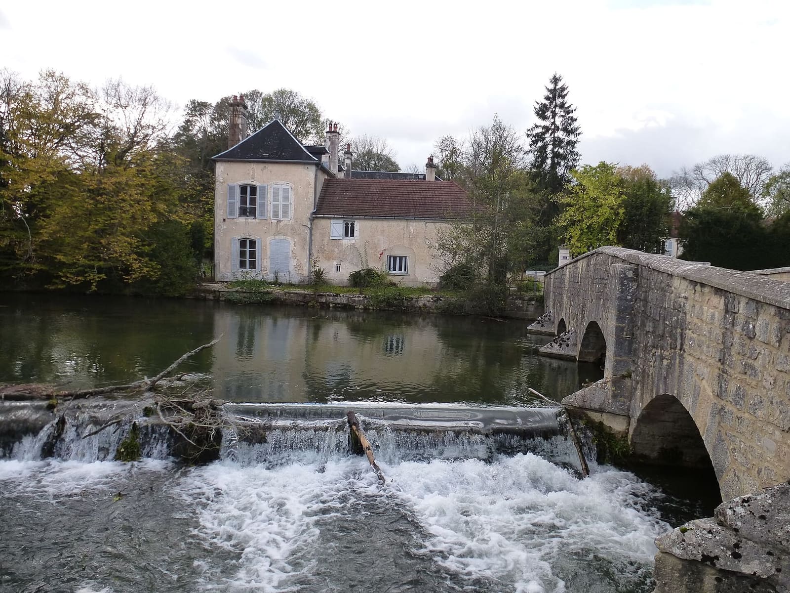 le pont de pierre sur la Laignes aux Riceys, avec la petite cascade et une maison sur la rive