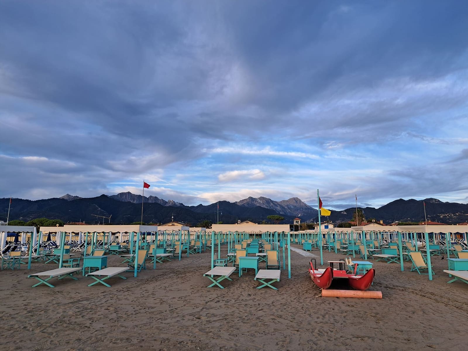 les établissements de plage avec les tentes et un pattino, la barque des maîtres-nageurs, sur le sable, sous les Apuanes