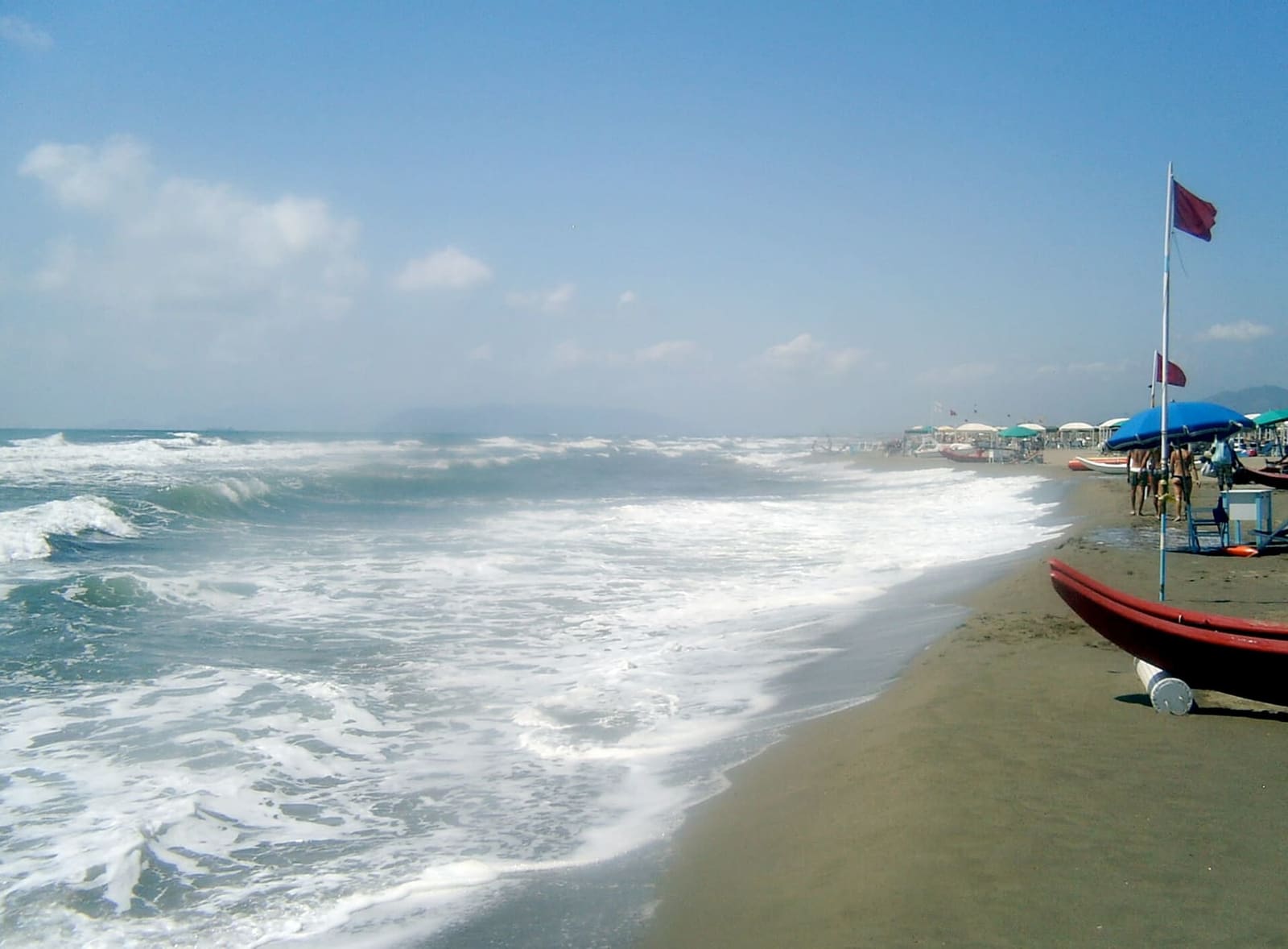 la mer agitée sur la plage de Forte dei Marmi, avec un pattino rouge et les parasols