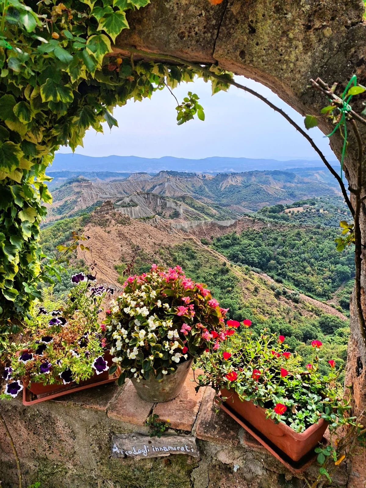 i calanchi visti da un arco coperto d'edera, con i fiori sul davanzale