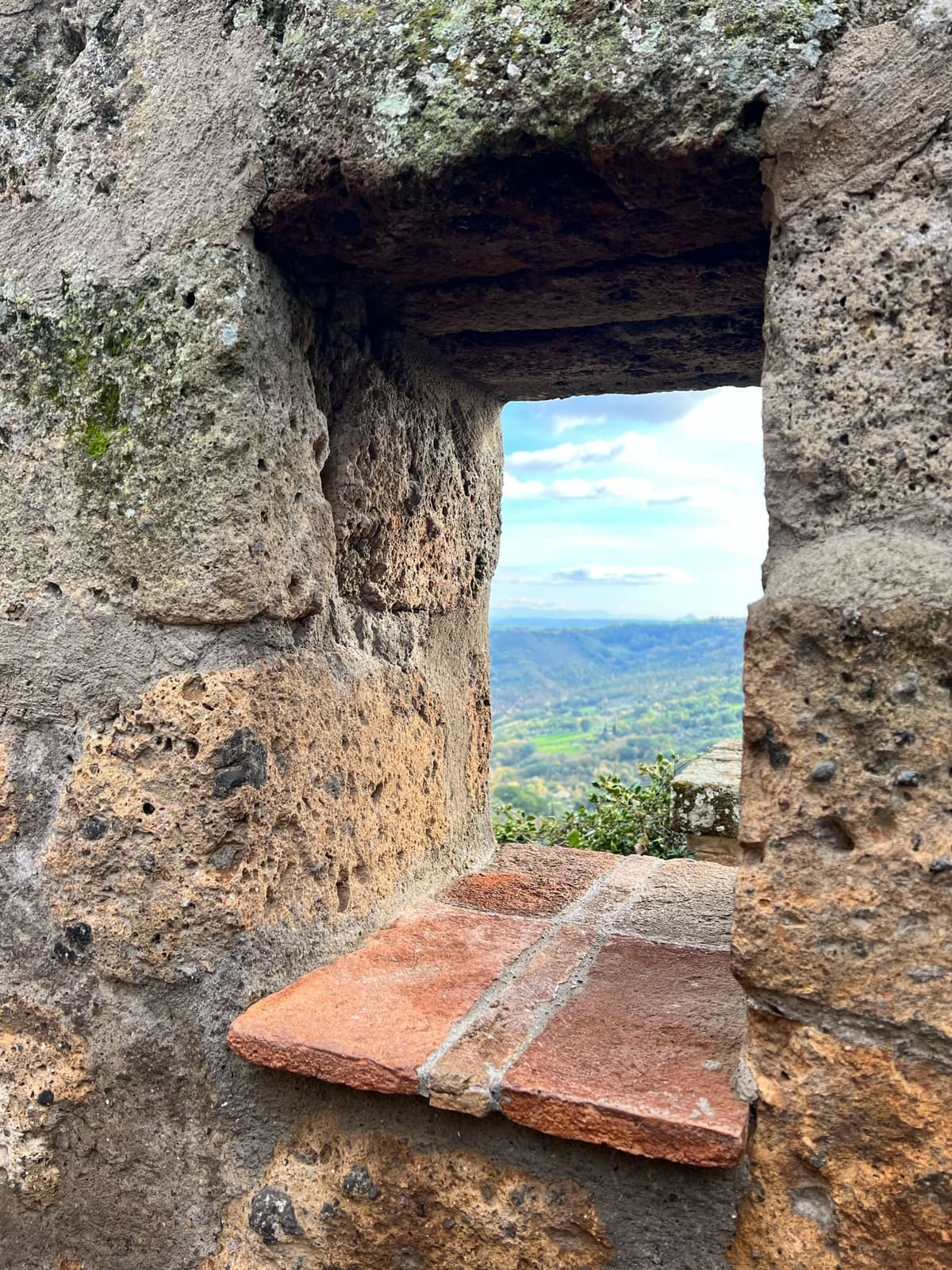una finestra scavata nel tufo, con il davanzale di cotto, aperta sulla valle