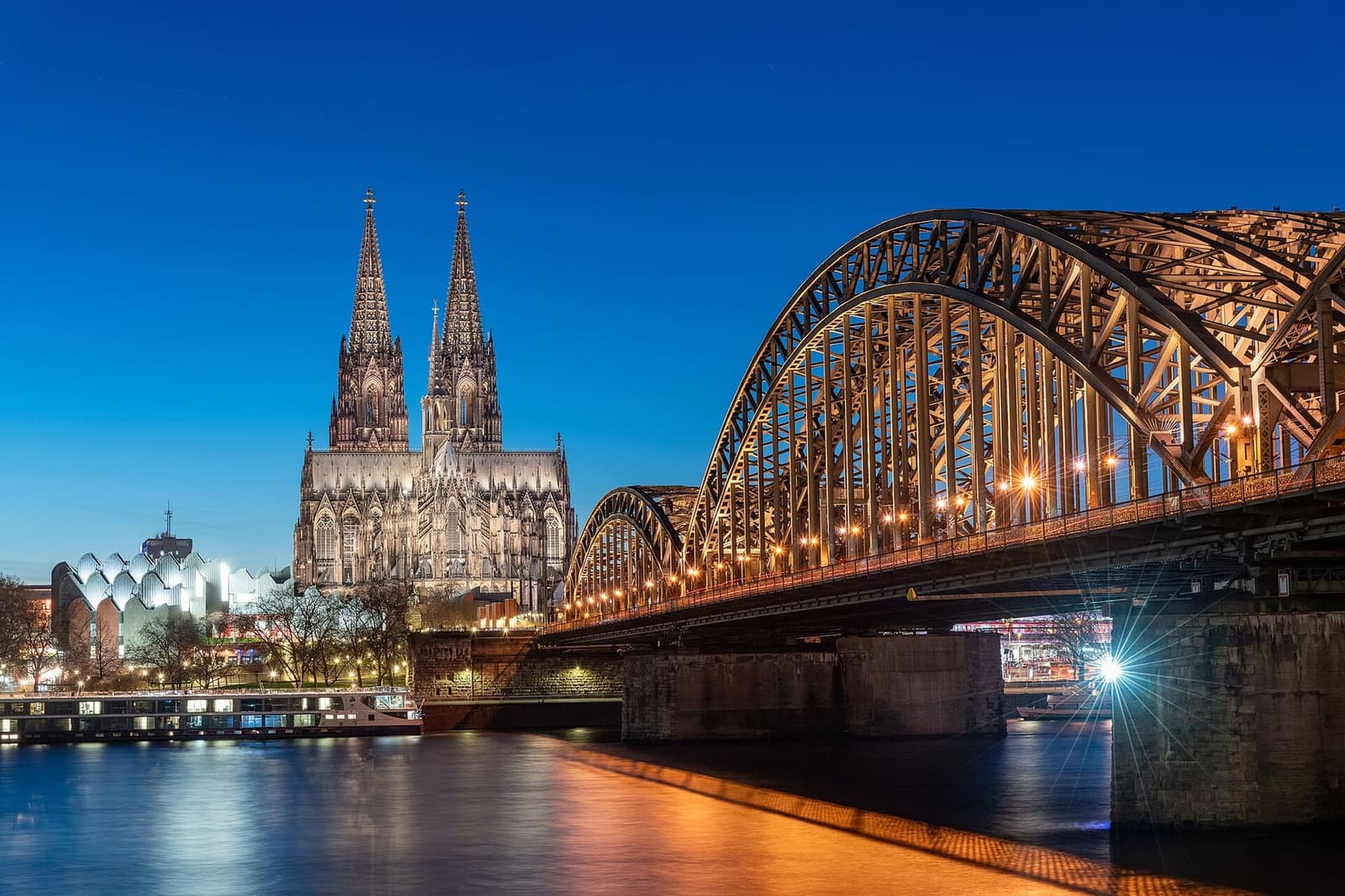 il ponte Hohenzollern illuminato e il Duomo che si riflettono nel Reno all'ora blu