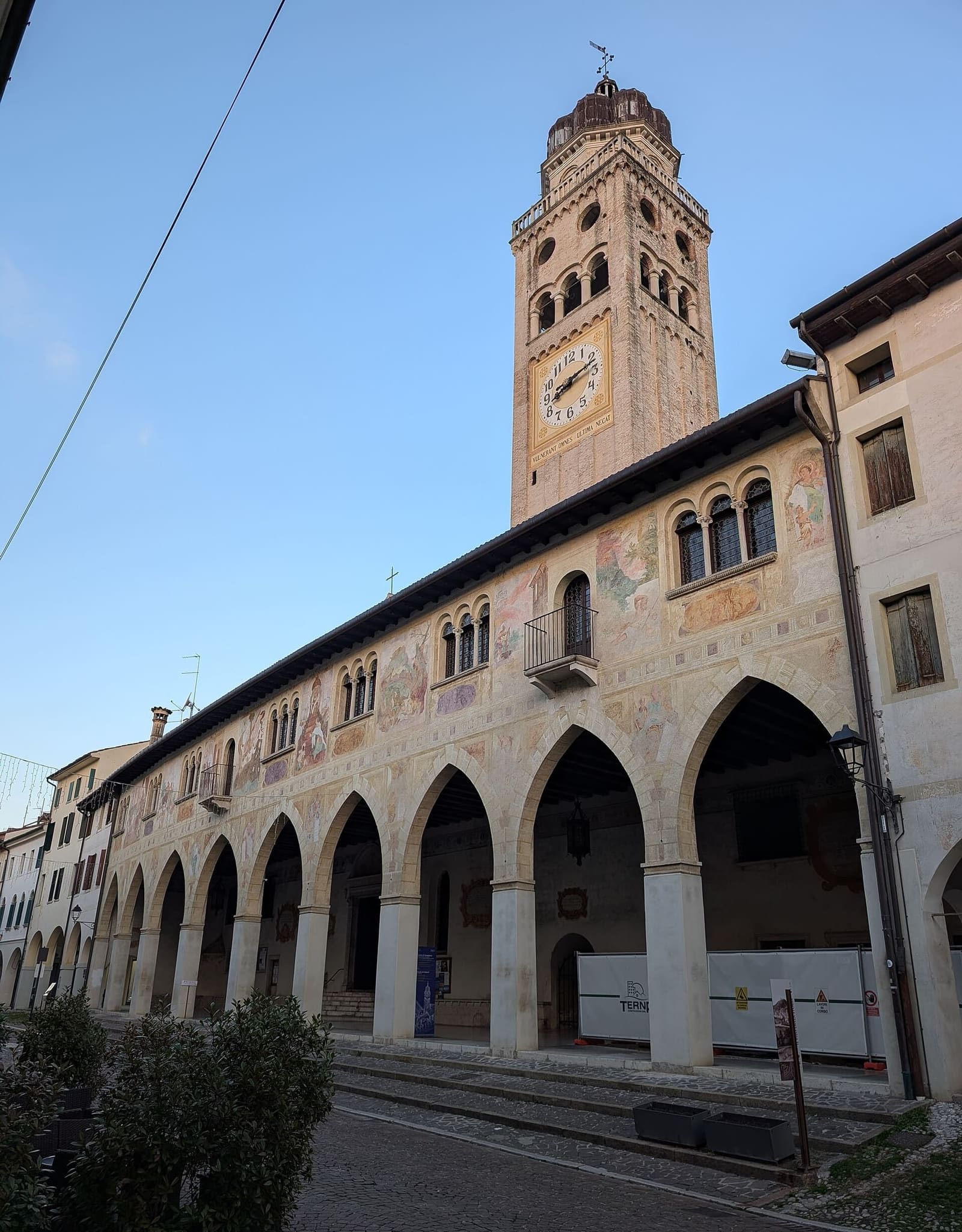 la facciata affrescata della Scuola dei Battuti sopra il portico del Duomo, con il campanile