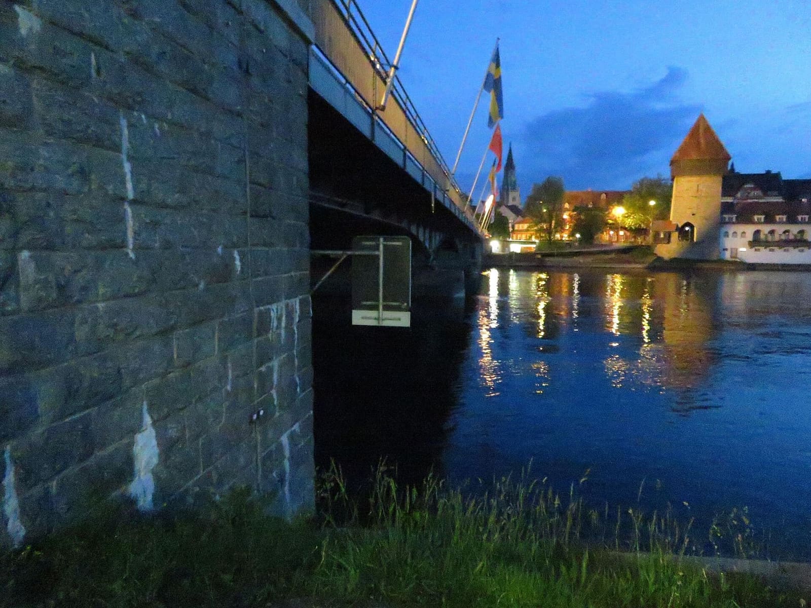 il ponte sul Reno e il Rheintor illuminati la sera, visti dalla riva