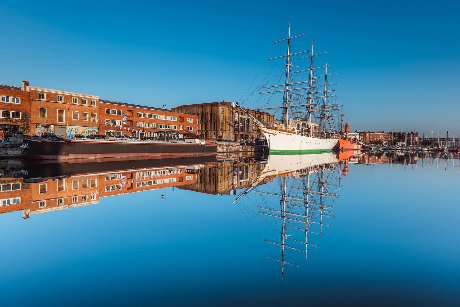 the Duchesse Anne, the red Sandettié and the Guilde barge reflected in the still water of the basin, in front of the Musée portuaire