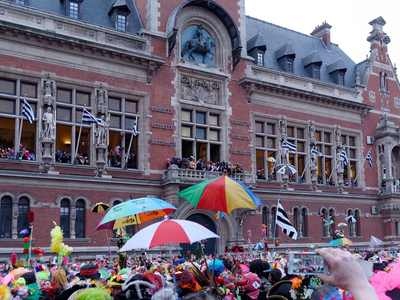 the herring throw from the balconies of the Hôtel de ville, with the carnival crowd and umbrellas below