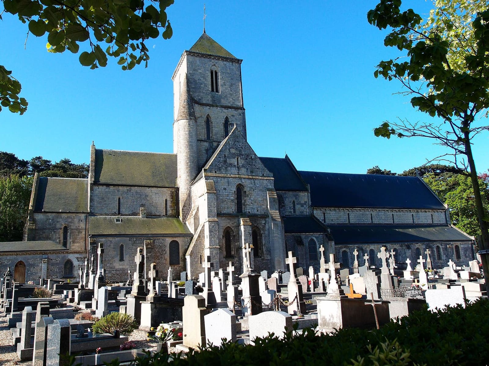 die Église Notre-Dame mit dem Vierungsturm, hinter den Gräbern des Friedhofs, im Mai