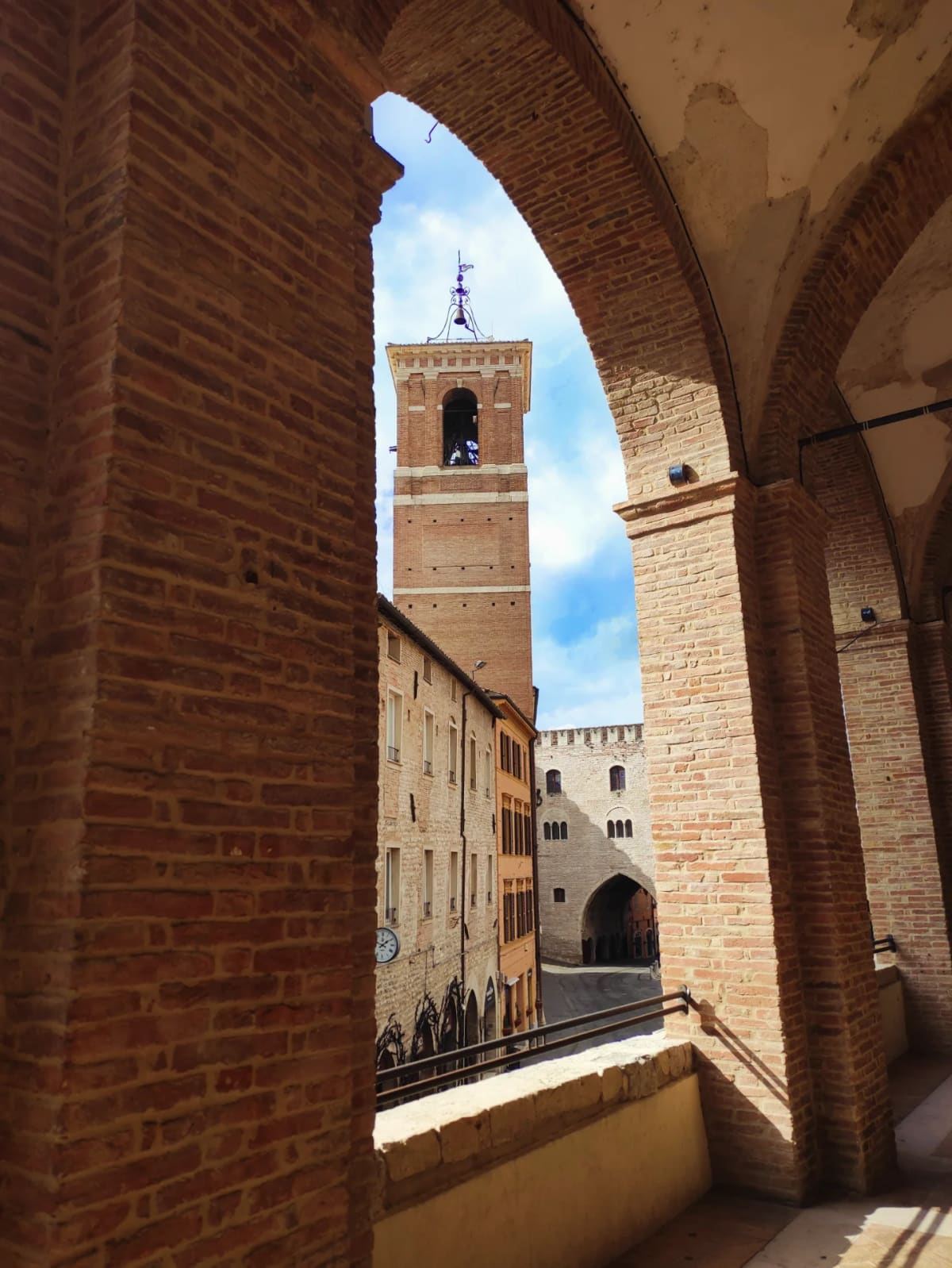 il campanile inquadrato da un arco del loggiato, con i tetti e la torre merlata sotto