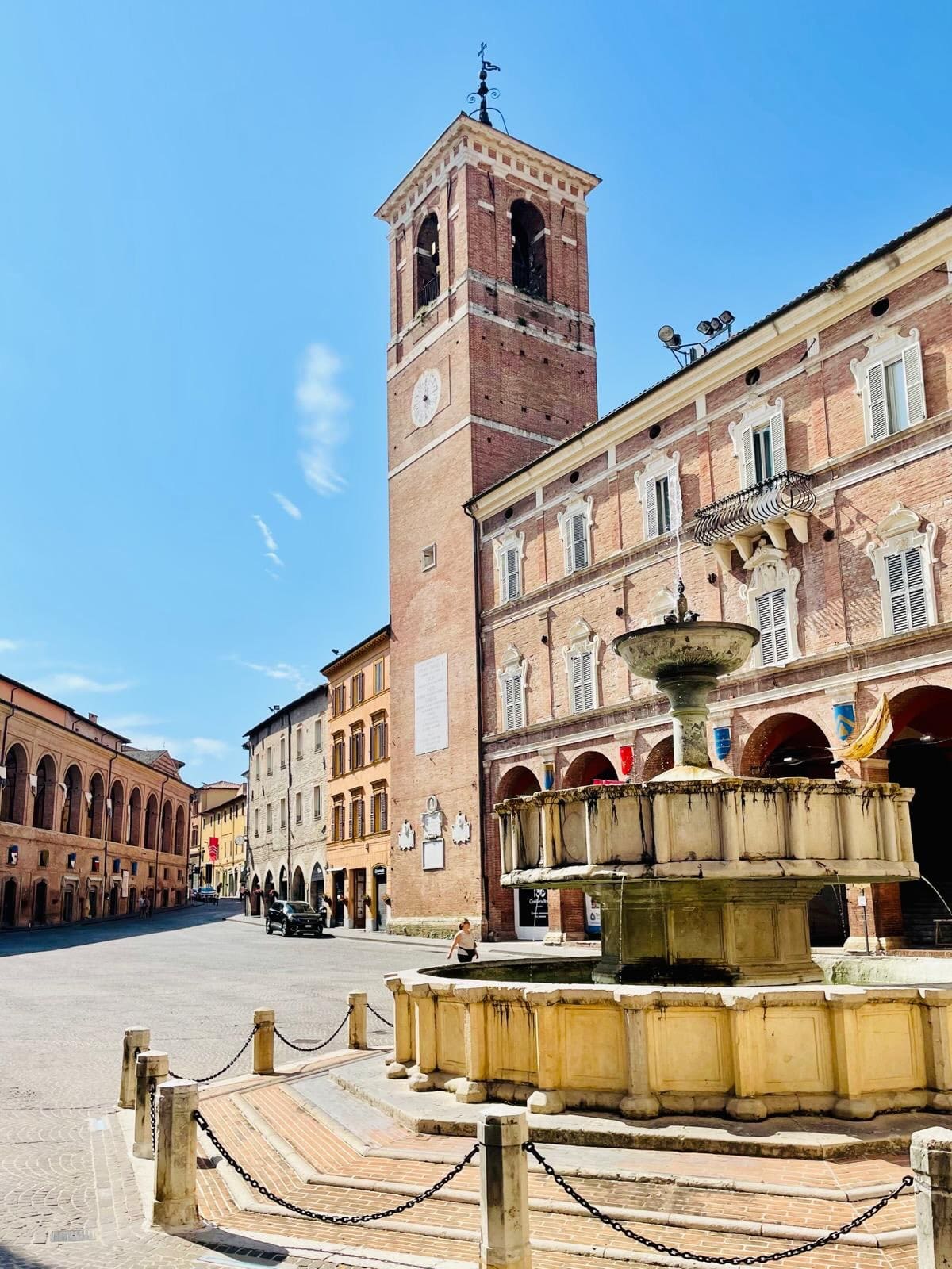 piazza del Comune con la fontana Sturinalto in primo piano, il campanile dietro e i portici che chiudono i lati