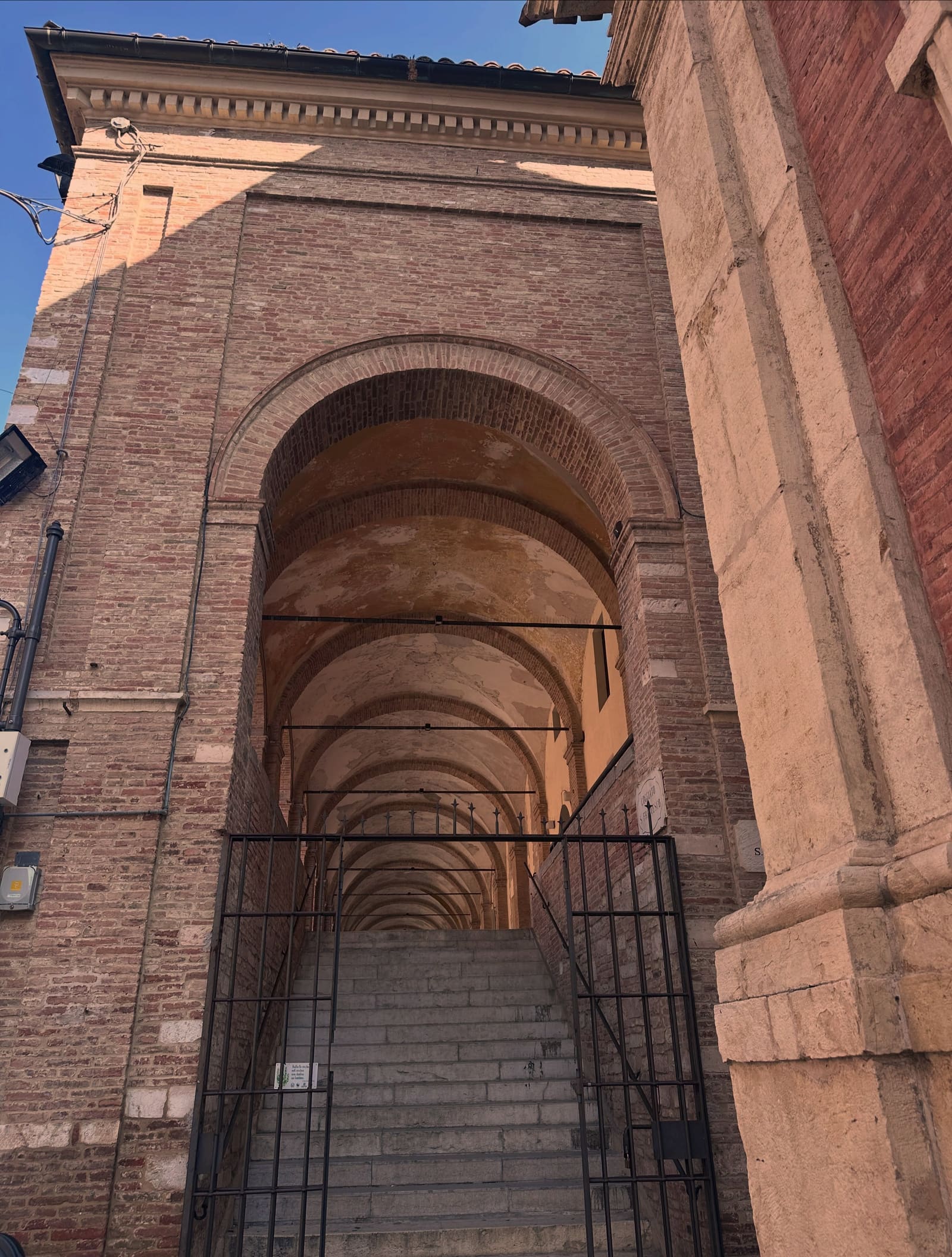 la scalinata che sale dentro il loggiato, con la fila di volte che si rimpiccioliscono verso il fondo