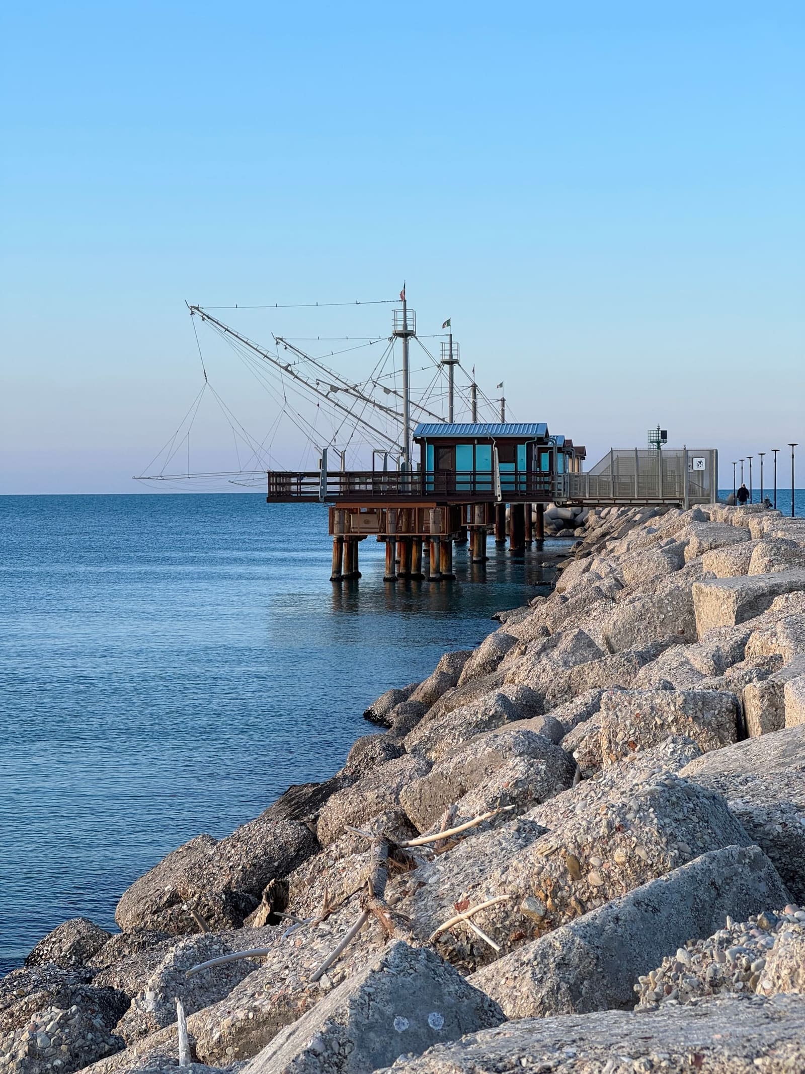 un trabucco visto dagli scogli, con le antenne aperte e la rete quadrata sospesa sull'acqua