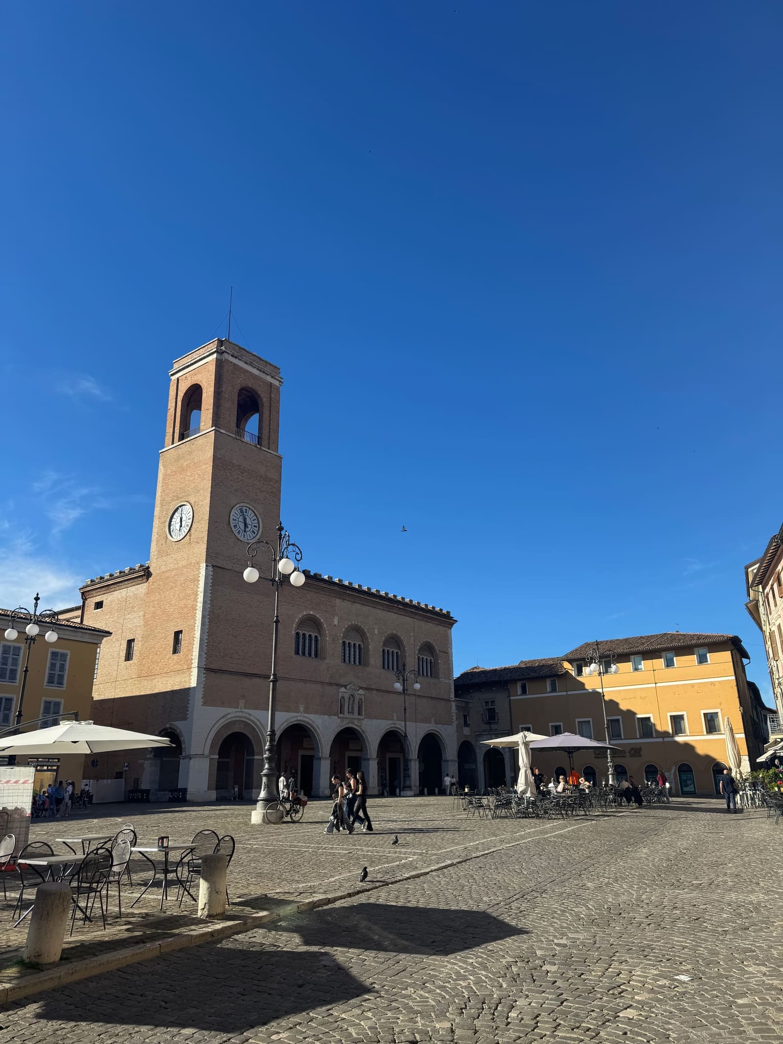 piazza XX Settembre con la torre civica e i tavolini dei bar, la sera