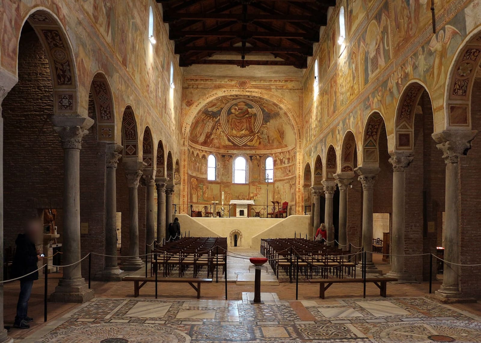 la navata della chiesa di Pomposa con gli affreschi sulle pareti e il pavimento a mosaico