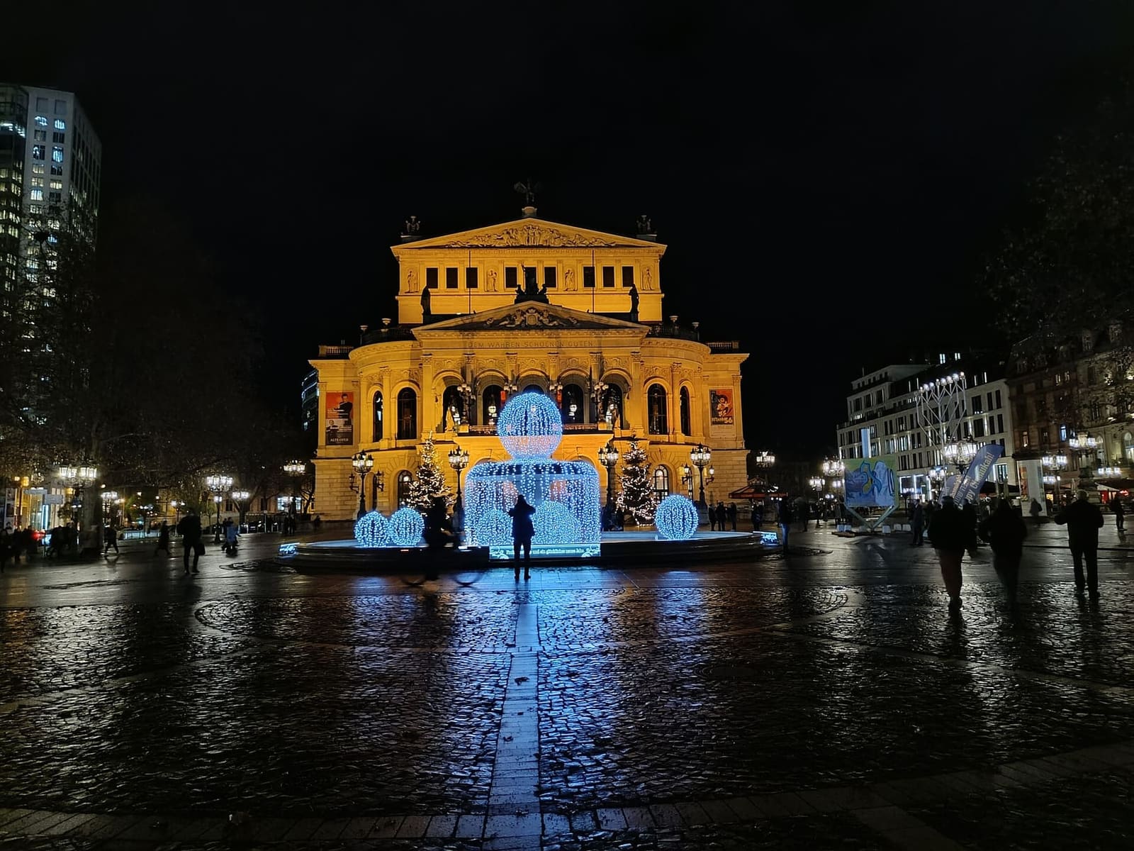l'Alte Oper illuminata in una sera di dicembre, con le decorazioni luminose sulla piazza bagnata