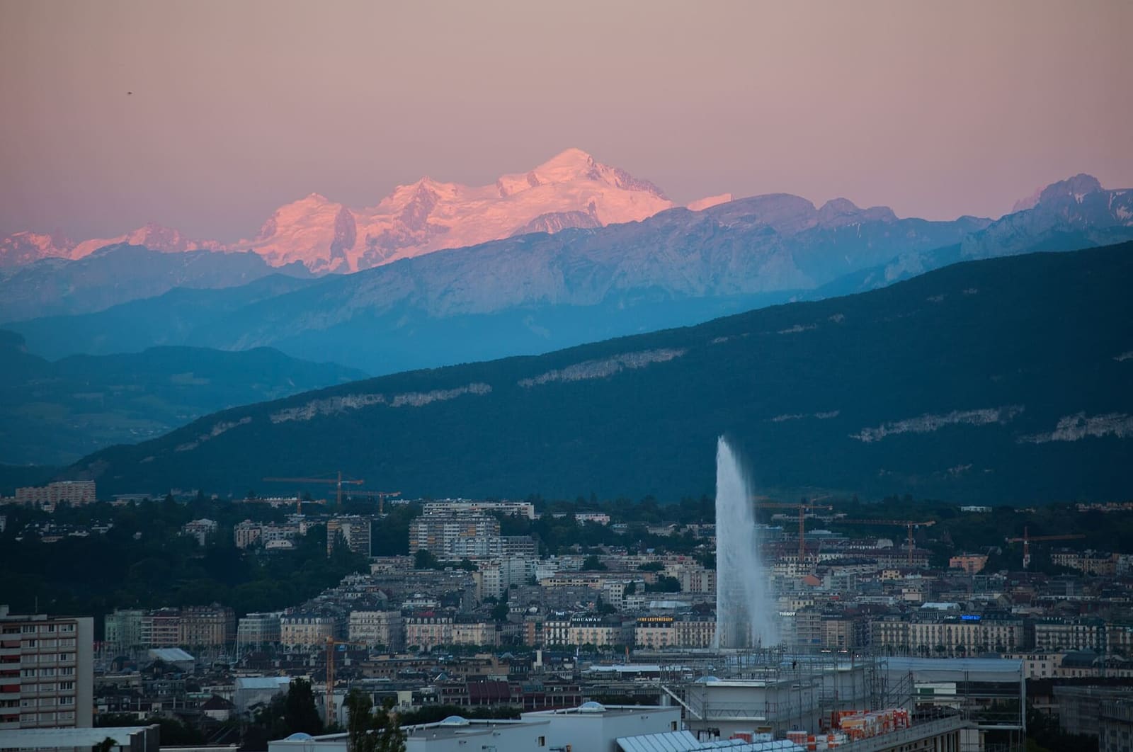 il Jet d'eau e il Monte Bianco rosa al tramonto, sopra i tetti della città