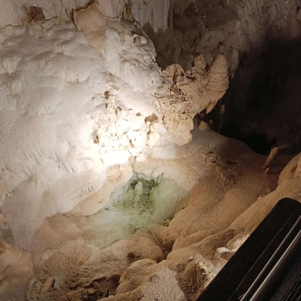 la colata bianca che finisce in una pozza verde chiaro, e a destra il corrimano della passerella