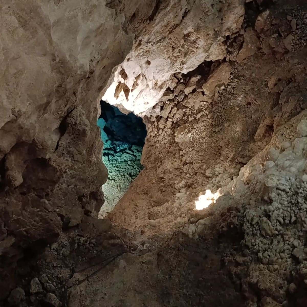 uno spiraglio nella roccia, e dietro l'acqua illuminata di turchese in una sala che non si attraversa