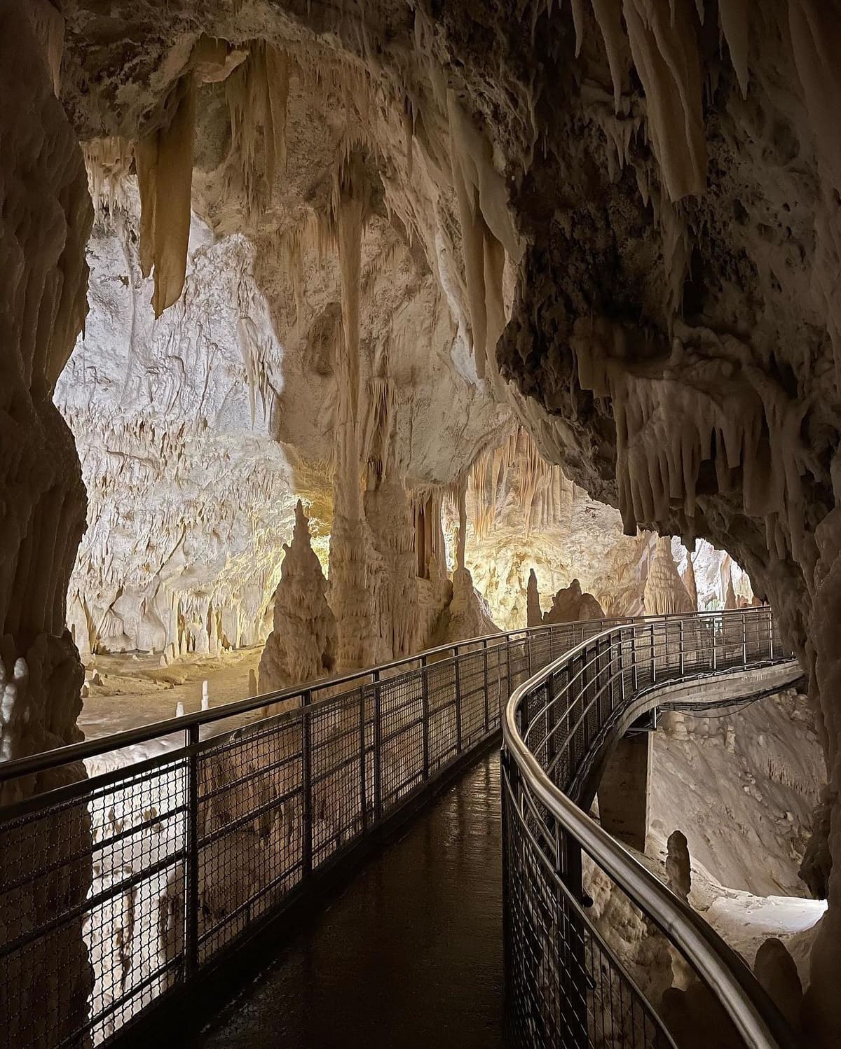 la passerella che curva e sparisce dentro la sala successiva, con le concrezioni illuminate di là