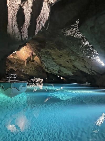una barca ormeggiata sull'acqua turchese, con le stalattiti sopra