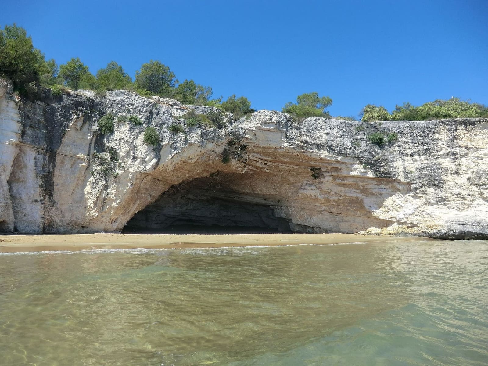 der Strand und die Grotta dei Colombi, in die weiße Steilküste gegraben, an der Küste von Vieste